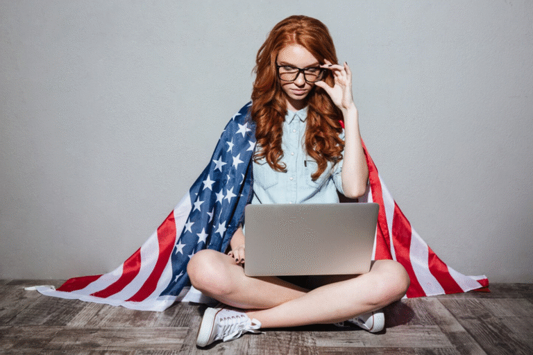 Młoda kobieta z flagą USA przy laptopie ucząca się angielskiego online z Milicza